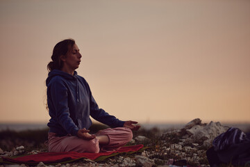 Woman practicing yoga outdoors in sunset sunrise time.