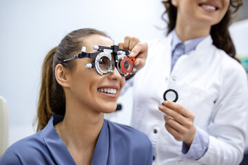 Ophthalmologist examining woman with optometrist trial frame. female patient to check vision in ophthalmological clinic - obrazy, fototapety, plakaty