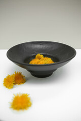 Beautiful beige and black plates. Dandelion flower in vase. Table design. Minimal decor