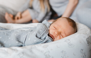 Close portrait of newborn boy in cocoon. Happy caucasian family of four people. Baby boy infront of his family. Selective focus. Film grain