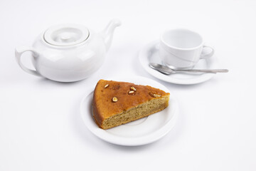 A piece of cake on a saucer with a cup for tea or coffee and a kettle