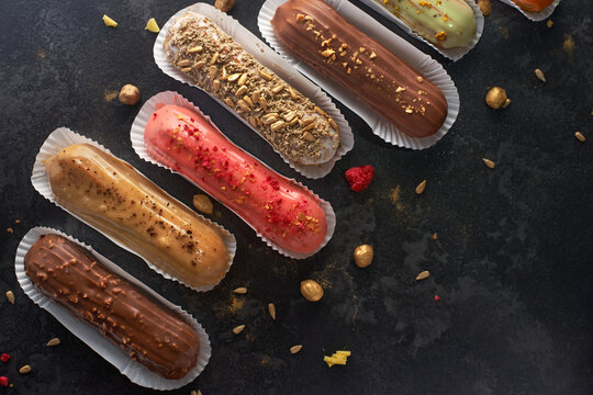 Traditional French dessert. Assorted eclairs on a dark stone background. flat lay, banner