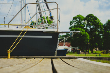 view on sailboat moored on wooden jetty in the port, close up view on sailboat hull and bow