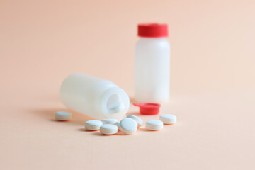 Medication, rounded white tablets and small bottles on a light background.