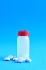 Medication, rounded white tablets and small bottle on a blue background.