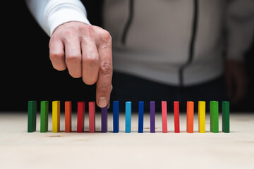 Conceptual photo of a hand picking up a stone from a row of domino stones.
Domino effect with...