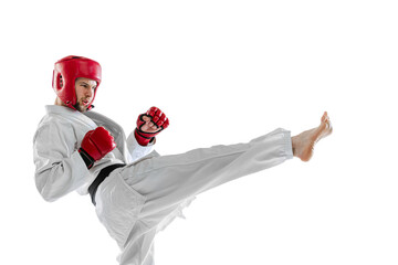 Portrait of young sportive man, taekwondo fighter wearing white dobok, helmet and gloves practicing...