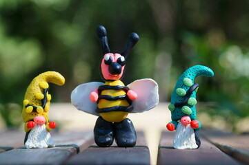 A figurine of a fabulous bee and dwarfs on a colored background. Bright magical characters from fairy tales.