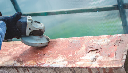 a man is grinding a board. Removing old paint from boards. Carpentry work.