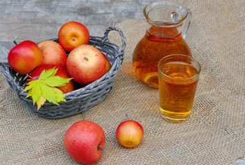 Korb mit roten Äpfeln und frischer Apfelsaft im Glas.    