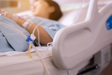 Picture of saline intravenous or iv solution on sickbed with blured patient in hospital