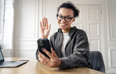 Video communication freelancer woman online working in the office, report to the company finance. Uses phone online work site.