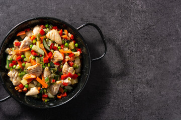 Chicken stir fry and vegetables on black stone. Top view. Copy space