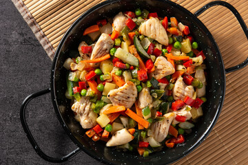 Chicken stir fry and vegetables on black stone. 
