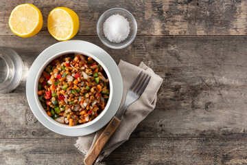 Lentil salad with peppers,onion and carrot in bowl on wooden table. Top view. Copy space