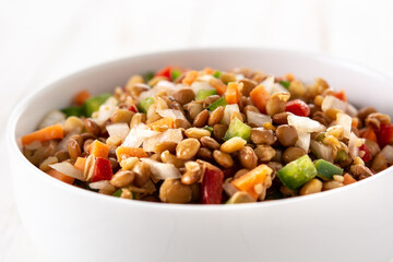 Lentil salad with peppers,onion and carrot in bowl on wooden table	