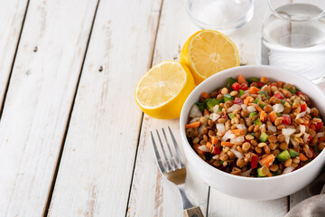 Lentil salad with peppers,onion and carrot in bowl on wooden table. Copy space