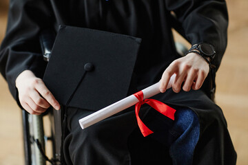 Close up of young man with disability at graduation ceremony in university holding diploma, copy...