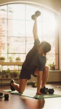 Vertical Screen: Strong Athletic Fit Young Man Doing Core Strengthening Exercises with Dumbbells During Morning Workout at Home in Sunny Apartment. Concept of Healthy Lifestyle and Fitness.