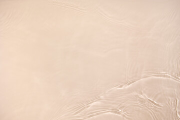 Transparent beige clear water surface texture with ripples, splashes. Abstract nature background Water waves in sunlight with copy space, top view. Cosmetic moisturizer micellar toner emulsion