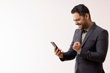 Young businessman cheering while received good news by email on mobile phone