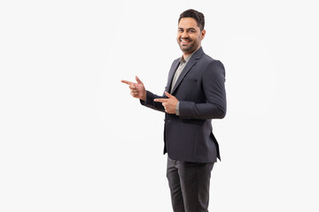 Cheerful young businessman pointing sideways against white background