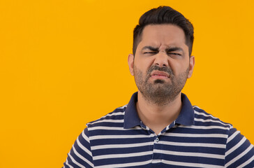 Fototapeta premium Portrait of a young man with annoyed facial expression against yellow background
