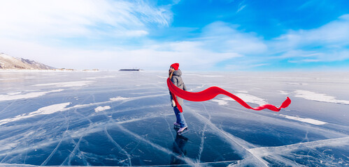 Concept Amazing winter photography tourism banner. Young woman tourist on ice skates and with long red scarf on frozen lake Baikal