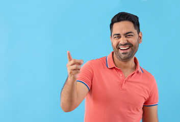 Fototapeta premium Portrait of smiling young man pointing elsewhere against blue background