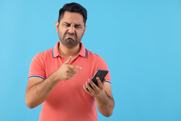 Portrait of a young man with displeased facial expression pointing at his Smartphone