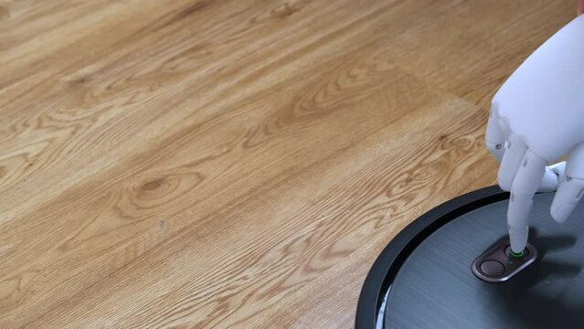 People with special needs. The prosthetic hand presses the button of the robot vacuum cleaner. The concept of doing housework by a disabled person. Loss of a limb, prosthetics. Manufacturability of