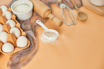 Fototapeta na wymiar Bakery or cooking frame, ingredients, kitchen items for pastry on pastel orange background. Top view, copy space.