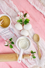 Fototapeta na wymiar Bakery or cooking frame with flowers, ingredients, kitchen items for pastry on pink background, spring cooking theme. Top view, copy space.