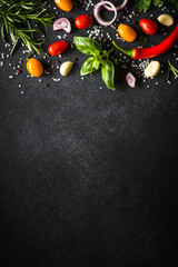 Food background on black kitchen table with fresh vegetables, herbs and spices. Ingredients for...