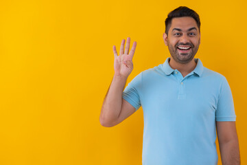 Portrait of a cheerful young man showing number with his fingers against yellow background