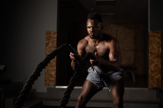 Attractive african american man with naked torso doing endurance exercises with trope. 