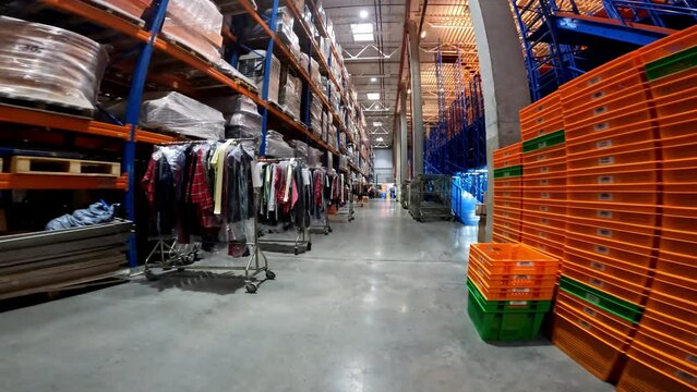 The clothes are hung in rows in the warehouse. Warehouse with clothes. Clothes in the warehouse of the factory. industrial interior