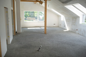 Construction site of attic conversion in the phase of floor screed fill and drywall is already in place and already partially spackled