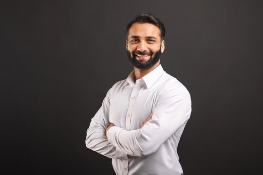 Proud Indian male businessman in white smart casual shirt stand with arms crossed isolated on black background, successful hispanic male entrepreneur in confident pose