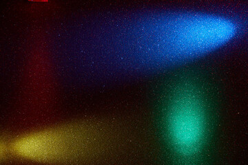 On a black background in multi-colored small grain multidirectional rays of blue green red and...
