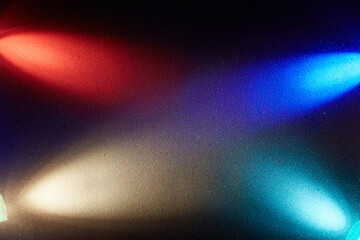 On a dark blue gradient background, crossed oncoming beams of blue red white and turquoise gradient light