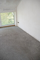 Construction site of attic conversion in the phase of floor screed fill and drywall is already in...