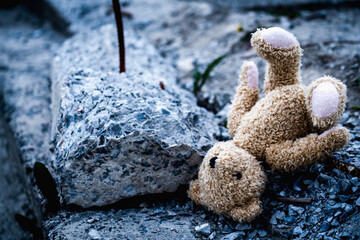 Children's toy teddy bear against the concrete background of destroyed building.