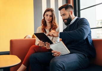 Business associates using a digital tablet in a lobby