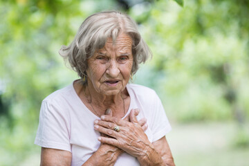 Elderly woman with heart pain holding her chest