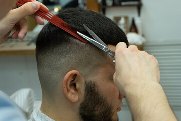 Barber cuts hair with scissors