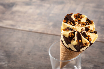 Vanilla and chocolate ice cream cone on wooden table. Copy space