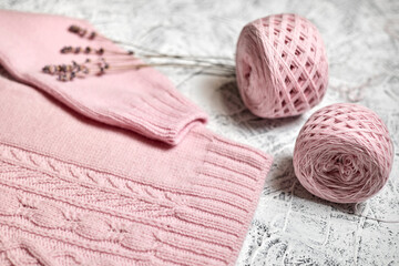 Pink knitted women's sweater with patterns and balls of thread