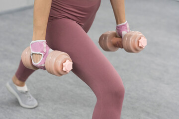 No face visible. Athletic young woman doing heavy lifting using dumbbell at the gym. Young woman...