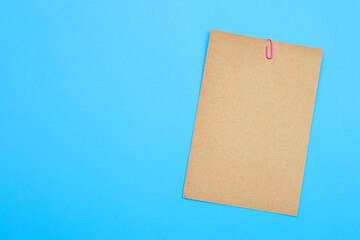 Brown paper with clip on blue background.